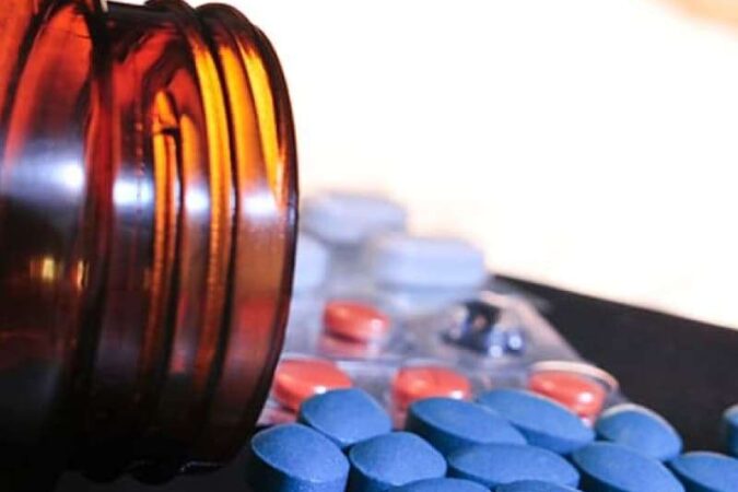Close-up view of spilled blue and orange pills from a brown bottle