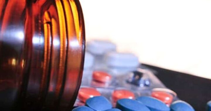Close-up view of spilled blue and orange pills from a brown bottle