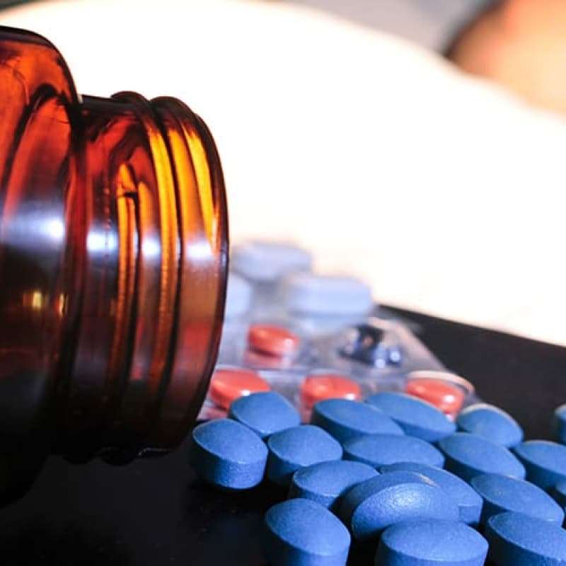 Close-up view of spilled blue and orange pills from a brown bottle